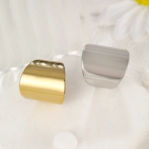 Polished 14k gold and silver open wide band rings displayed on a minimalist stone base