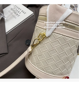 Detail of woven beige leather bucket bag with gold hardware and pink silk scarf accessory
