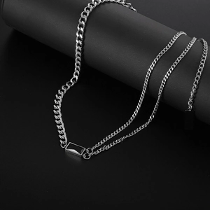Close-up of silver Cuban chain necklace with a rectangular black gemstone pendant