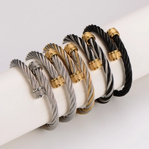 Minimalist stainless steel cable twist bangles in multiple colors on white pedestals