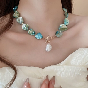 Close-up of Bohemian necklace with turquoise shell beads and a Baroque pearl pendant