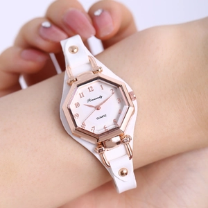 Gros plan d'une montre quartz pour femme avec boîtier hexagonal or rose et bracelet blanc