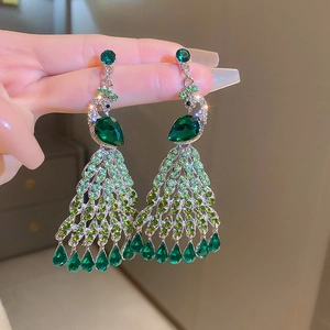 Close-up of green crystal peacock tassel earrings with silver needle and rhinestones