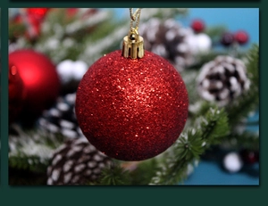 Macro shot of a red glitter Christmas ball ornament with sparkling texture on pine branches