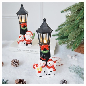 Close-up of lighted Christmas snowman street lamp on artificial snow with warm glow