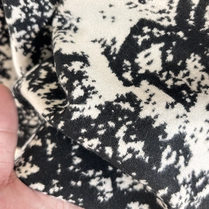 Macro detail of soft cashmere-feel knitted fabric with black and white abstract pattern
