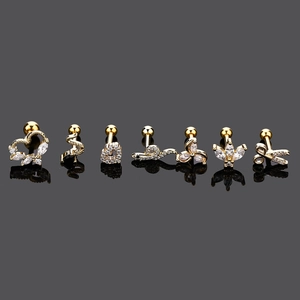 Detail view of seven gold stainless steel cartilage studs with heart and snake designs