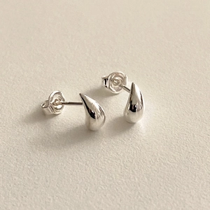 Nahaufnahme polierter S925 Sterlingsilber Tropfenohrstecker auf minimalistischem Grund