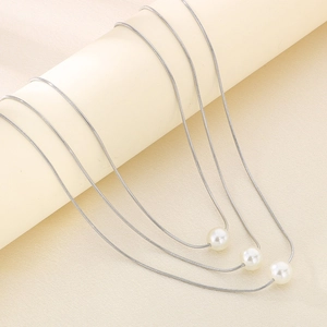 Detail of silver triple-layered snake chain necklace with elegant white pearl pendants