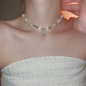 Detail of layered gold necklace with heart pendant, pearls and sparkling zircons on model