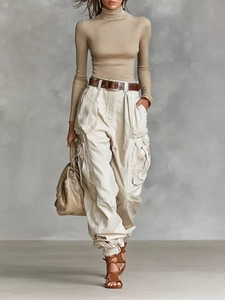 Full body view of high waist off-white cargo pants with tan knit top and leather belt