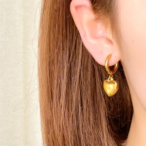 Détail d'un mannequin portant une boucle d'oreille pendante en forme de cœur doré brillant