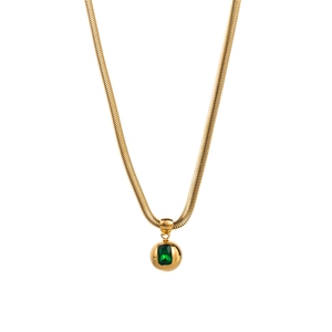 Macro detail of gold snake chain necklace with a green gemstone set in a sphere pendant