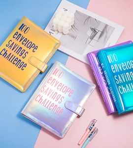 Flat lay of colorful holographic 100 envelope savings challenge binders for budgeting