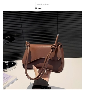 Detail of a brown leather shoulder bag featuring a unique knotted strap and flap closure