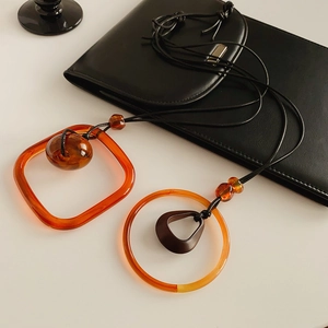Detail of vintage long wax cord necklaces featuring orange resin geometric pendants