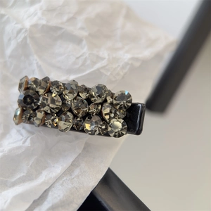 Détail d'une pince à cheveux noire ornée de strass gris foncé étincelants