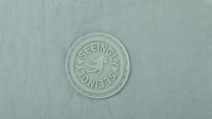 Close-up of waterproof nylon fabric with stitched circular logo detail on phone bag