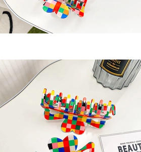 Close-up of a large checkerboard hair claw clip with colorful acrylic butterfly design
