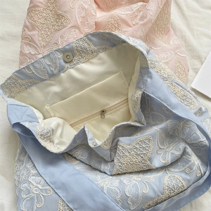 Detail of floral lace embroidery handbag featuring magnetic buckle and inner zipper pocket