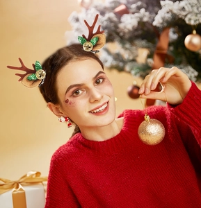 Close-up of model wearing plush reindeer antler hair clips with festive bells and earrings