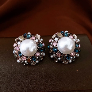 Macro shot of vintage round earrings with baroque pearls and colorful rhinestones