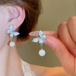 Detail of silver needle butterfly earrings with gradient crystals and hanging pearl