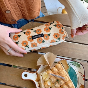 Detail of corduroy pencil case with orange floral patterns and metal ring zipper pull
