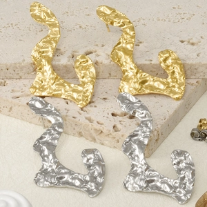 Macro shot of irregular pleated 304 stainless steel earrings in gold and silver finishes