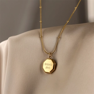 Detail of octagonal gold pendant with Forever Love engraving and beaded snake chain