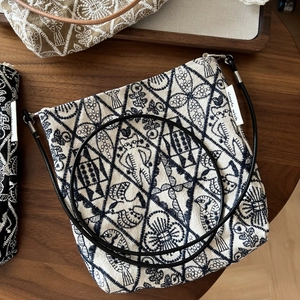 Detailed close-up of vintage embroidered canvas bag with cat motifs and leather strap