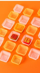 Macro view of pink and yellow square PP mooncake trays on an orange background
