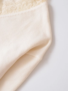 Detailed close-up of cream wool blend knit fabric with elegant floral lace embroidery