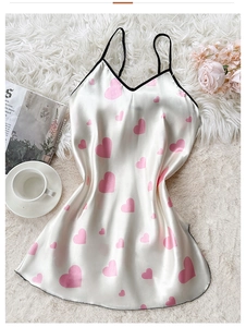 Close-up of white satin nightdress with pink heart print and black shoulder straps