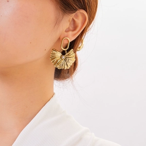Detail of 18K gold fan-shaped drop earring with white pearl worn by a model