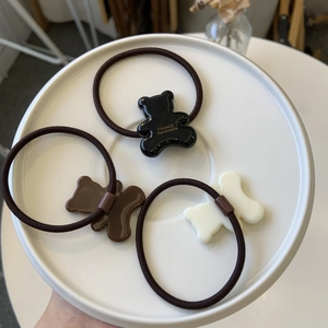 Lot de trois chouchous ours en noir, marron et blanc disposés sur une assiette blanche
