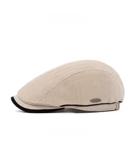 Detail view of beige herringbone newsboy hat with metal logo plate and contrast brim