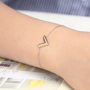 Minimalist V-shaped rose gold bracelet for women worn on wrist with subtle crossbody chain