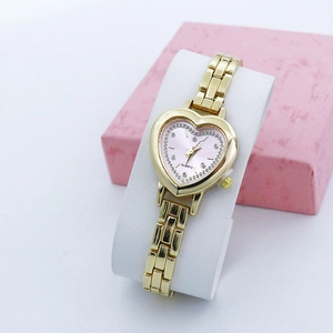 Detail of a heart-shaped gold quartz watch with pink rhinestone dial on a display stand