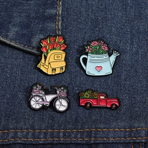 Lot de quatre broches en émail avec charrette à fleurs et vélo sur tissu denim