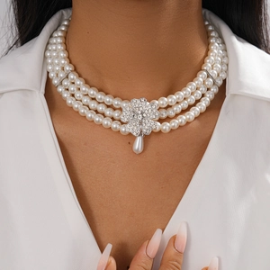 Detail of layered pearl necklace with rhinestone flower and teardrop pendant on model