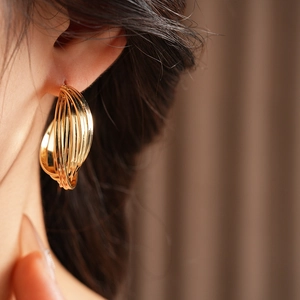 Close-up of model wearing gold multilayer hoop earrings with a twisted minimalist design