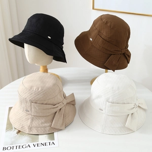Dettaglio di quattro cappelli da sole colorati con fiocchi in nero marrone beige e bianco