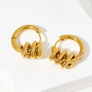 Minimalist spiral spring gold hoop earrings displayed on white plaster background