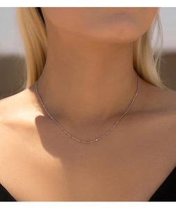 Macro shot of minimalist S925 sterling silver fine chain worn on a female neck