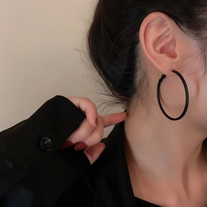 Close-up of a matte black hoop earring worn by a model in a minimalist style