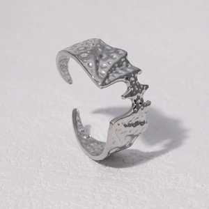 Macro detail of silver adjustable bat ring with unique lava rock texture on steel surface