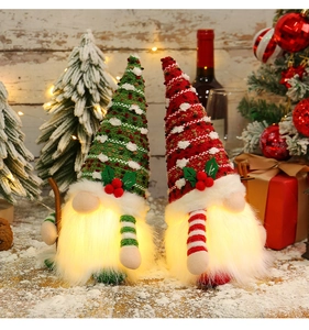Detail of two Christmas gnomes with warm LED lights and cozy knitted berry hats