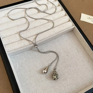 Macro detail of adjustable silver snake chain with polished metal and dalmatian stone charms