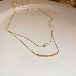 Double-layered gold necklace featuring a white pearl and spiral texture metal bar